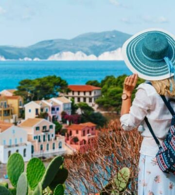 tourist-female-with-blue-sun-hat-and-travel-backpack-enjoying-greek-vivid-colored-assos-town-768x512